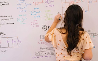 Person diagramming engineering work on a whiteboard